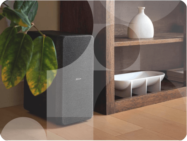 Compact subwoofer speaker placed next to wooden shelving unit in home interior.